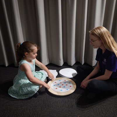 Young girl sitting with UQ PhD candidate manually rotating a turntable 